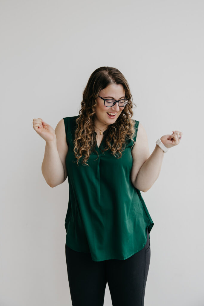 K.S.Otter Events' owner, Katie Sautter, playfully dancing in a green sleeveless top with a full head of curls